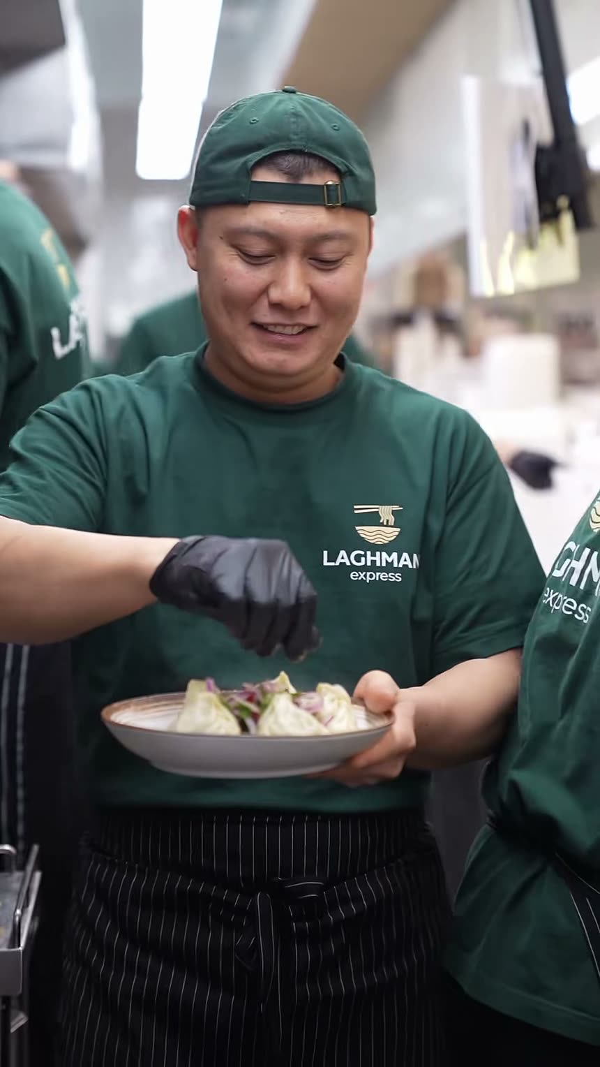 A cook carrying two finished plates out of the kitchen