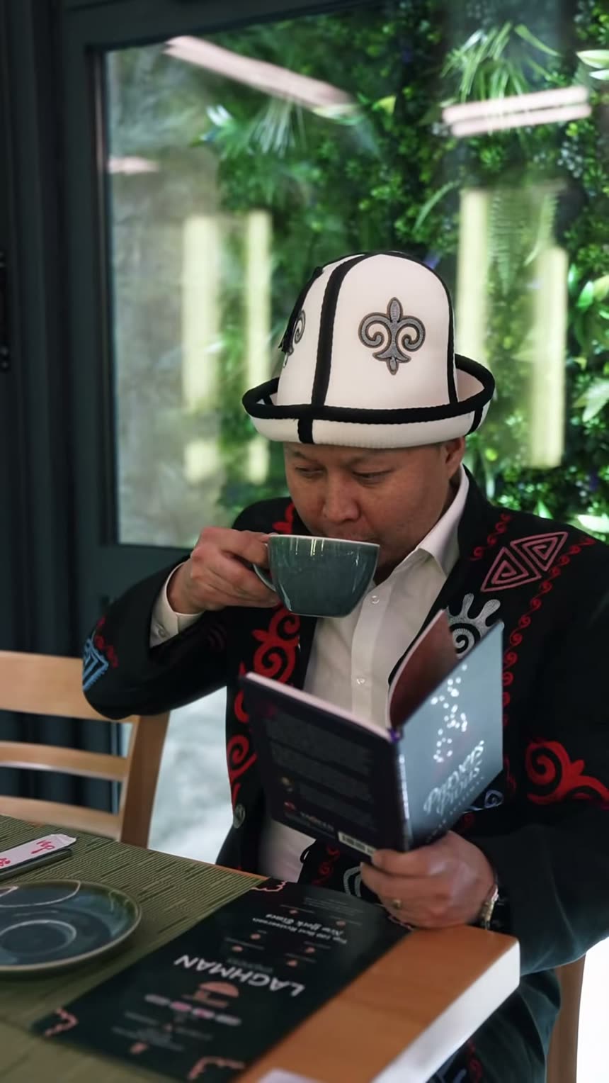 A guest in a traditional kalpak reading the menu over tea